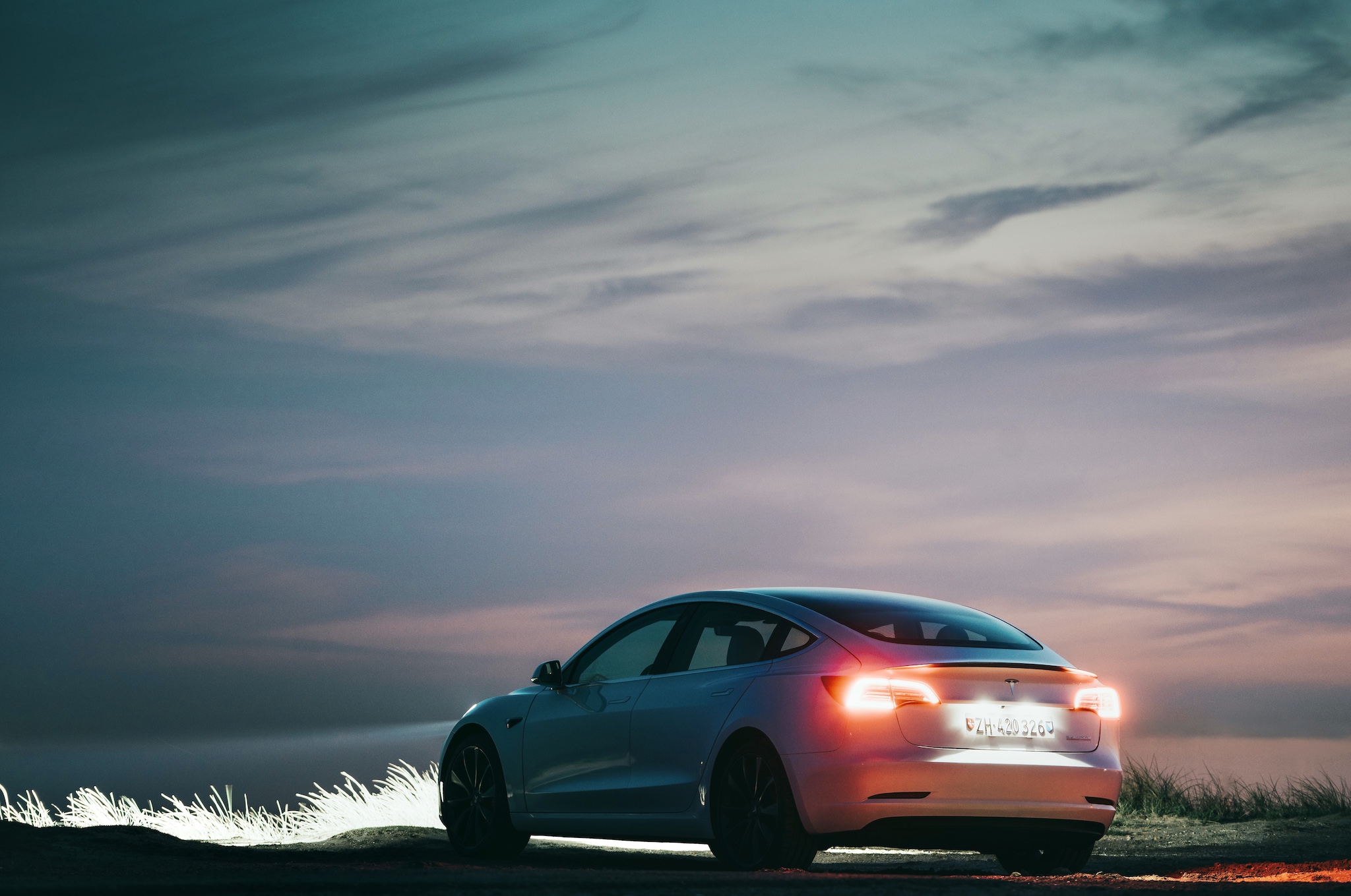 White Tesla Model 3 Performance in the dunes of Maasvlakte, Netherlands at night.