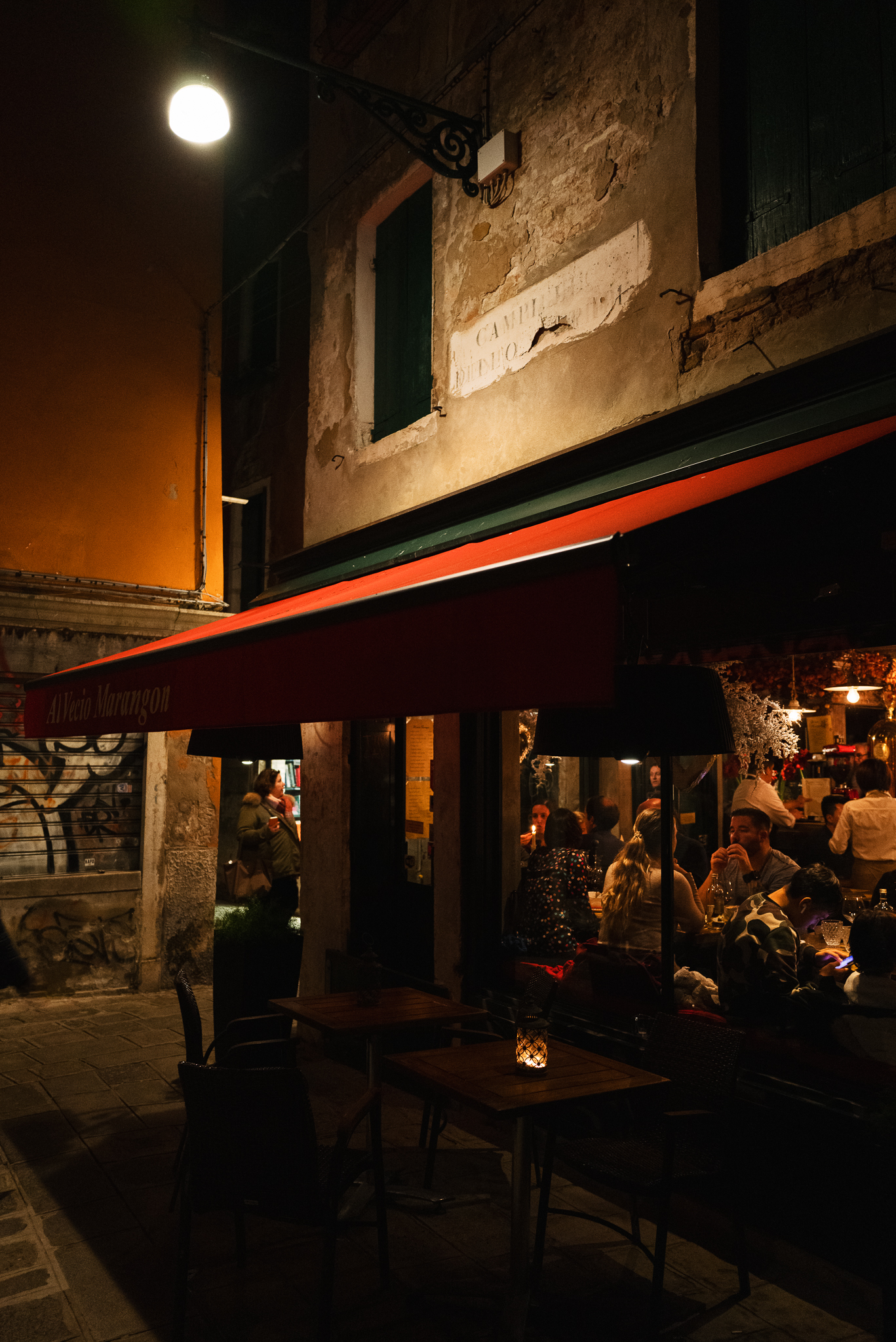 An alley with a cosy restaurent. People having a good time.