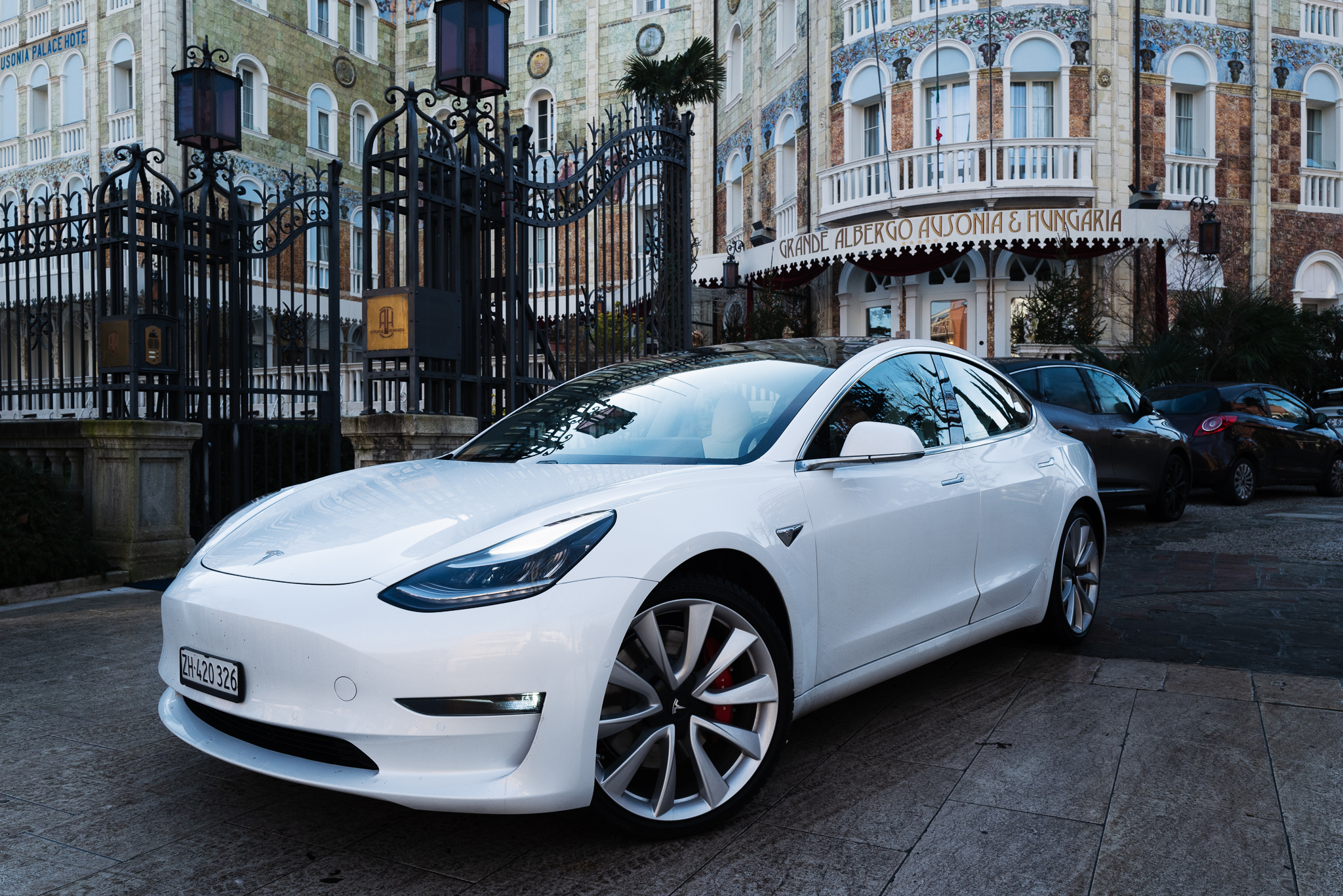 White Tesla Model 3 in front of hotel.